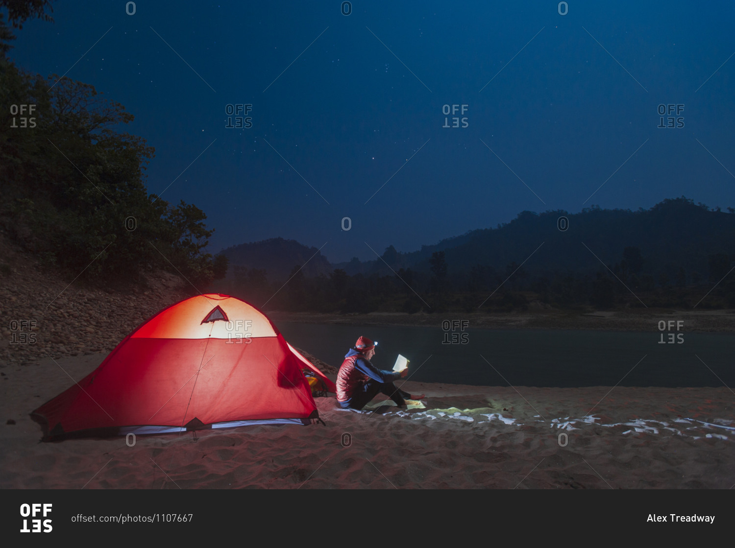 Reading by head lamp outside a tent during a river rafting trip on the Karnali river in west Nepal