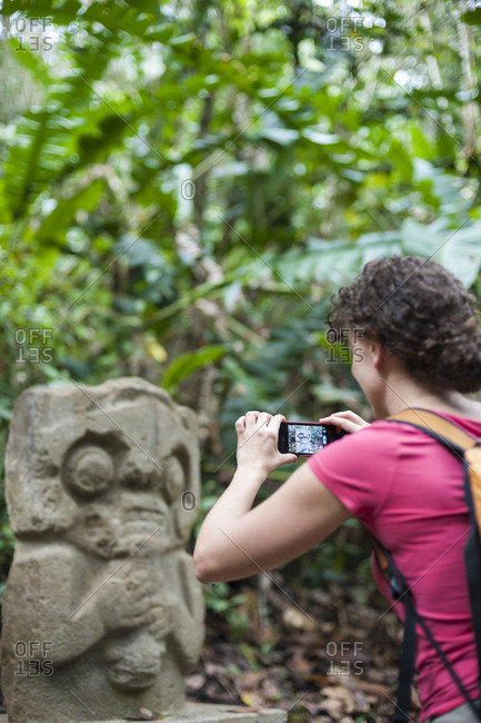 A woman takes a photo of an ancient statue with a smartphone at San Agustin in Colombia