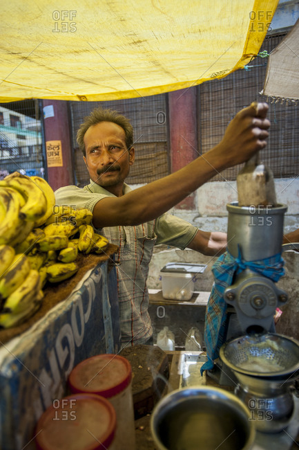 A fruit seller prepares a juice from his stall of fresh fruit