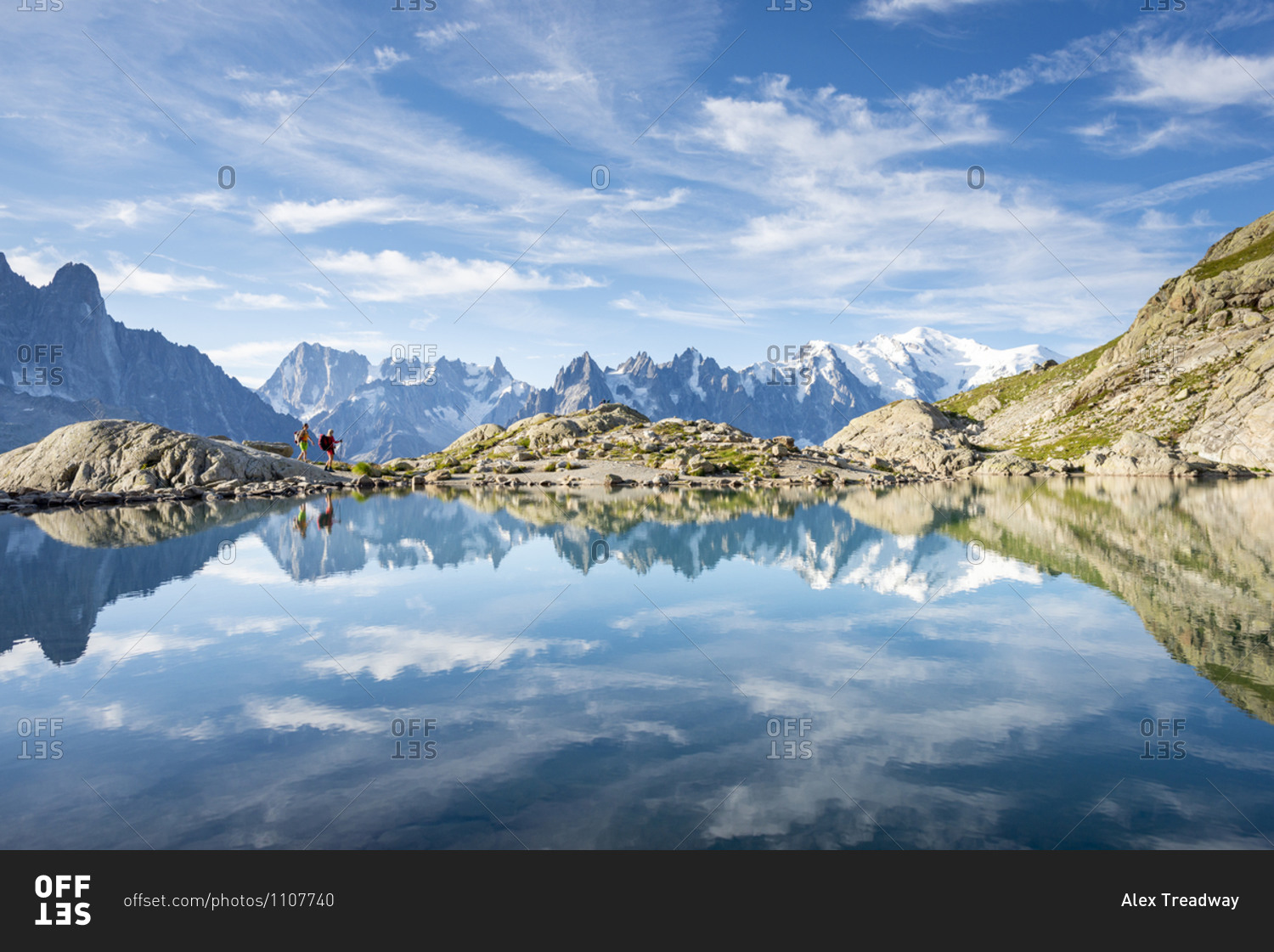Hikers and the summit of Mont Blanc reflected in Lac Blanc on the Tour du Mont Blanc trekking route in the French Alps
