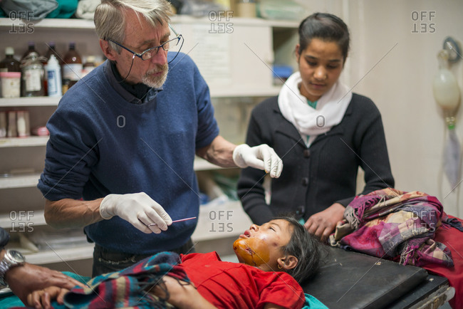 A doctor performs minor surgery on a young girl with an injured jaw at a hospital in Nepal