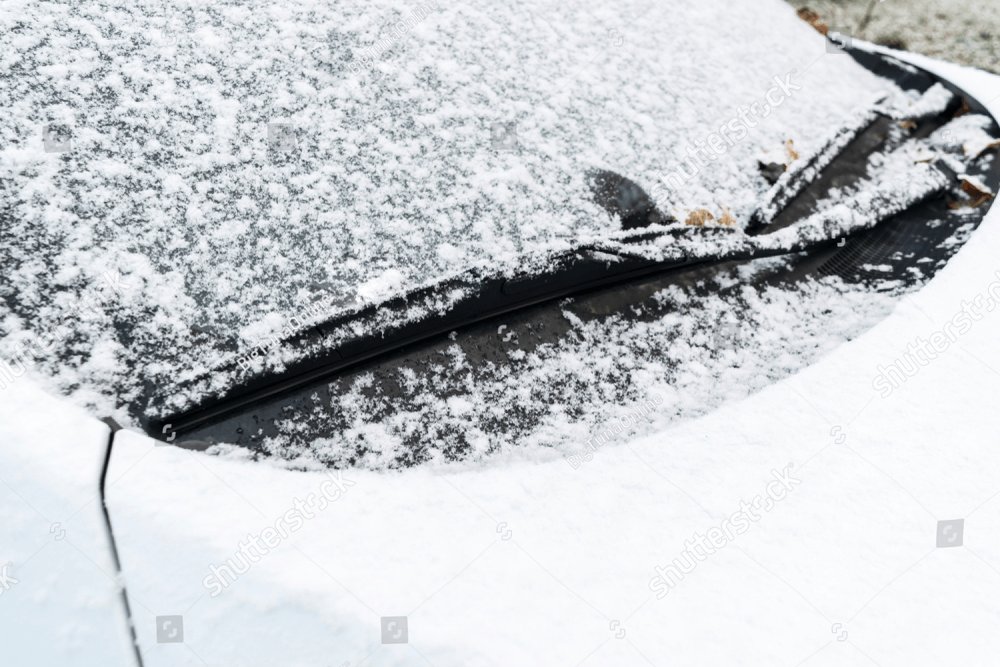 Snow covered car window with wipers, macro, close up. Car wiper blades  clean snow from car windows. Flakes of snow covered the car. Industrial  Stock Photos