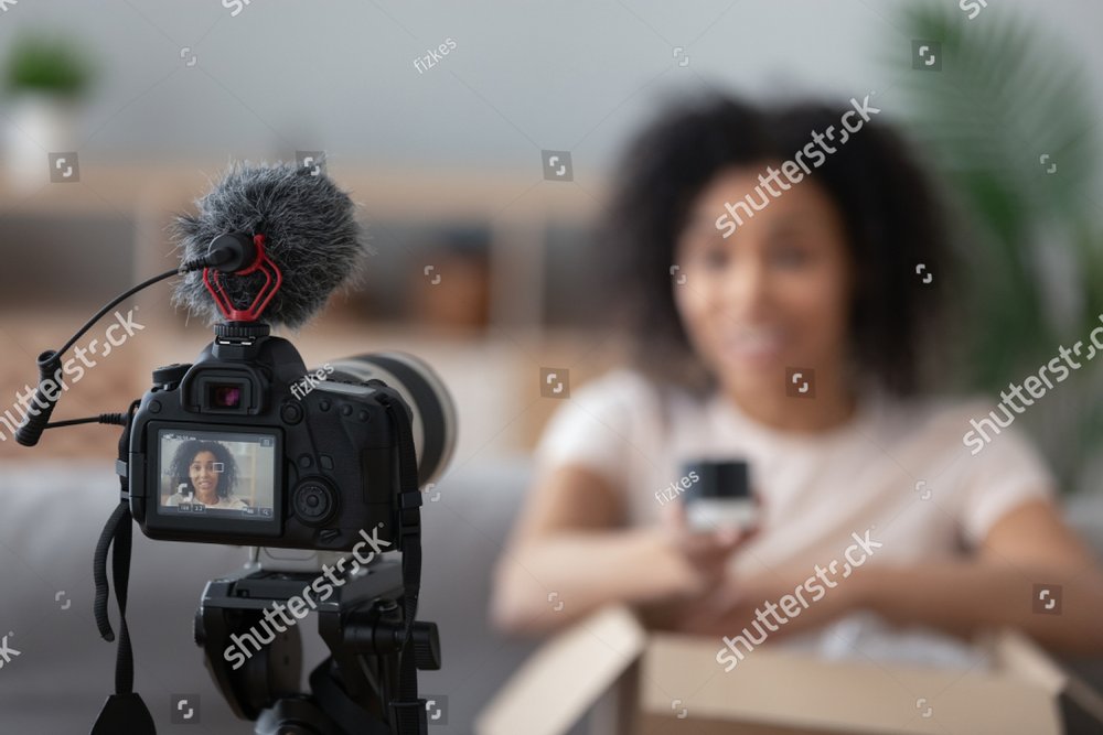 Professional camera device shooting african American young woman blogger making unpacking video at home, black biracial young woman vlogger influencer record content on cam, brand advertising promo