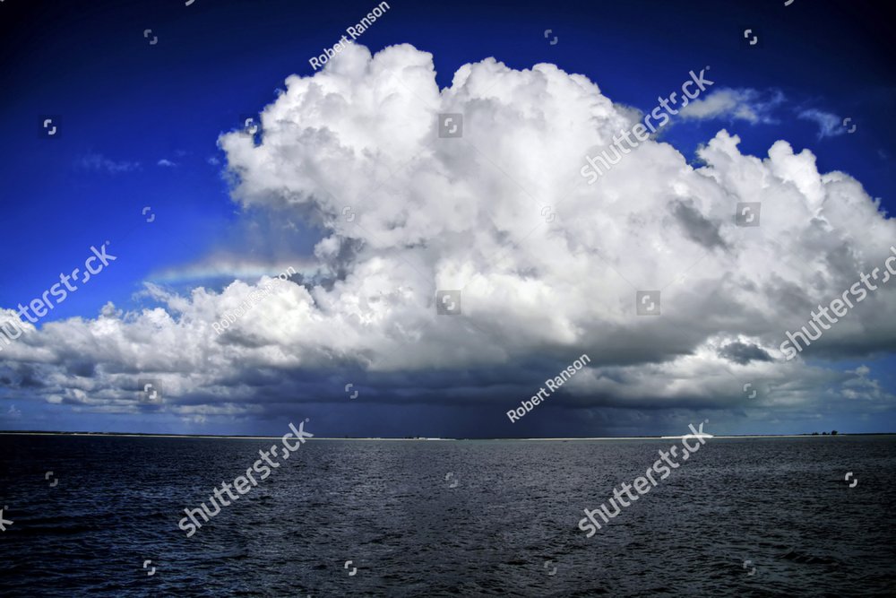 Big cumulus nimbus cloud with rainbow sticking out the a large cloud  over a body of water Nature Stock Photos Creative Market