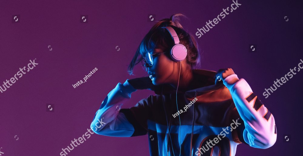 Hipster igen teen pretty fashion girl model wear stylish glasses headphones enjoy listen new cool music mix stand at purple studio background in trendy 80s 90s club blue party light, profile view