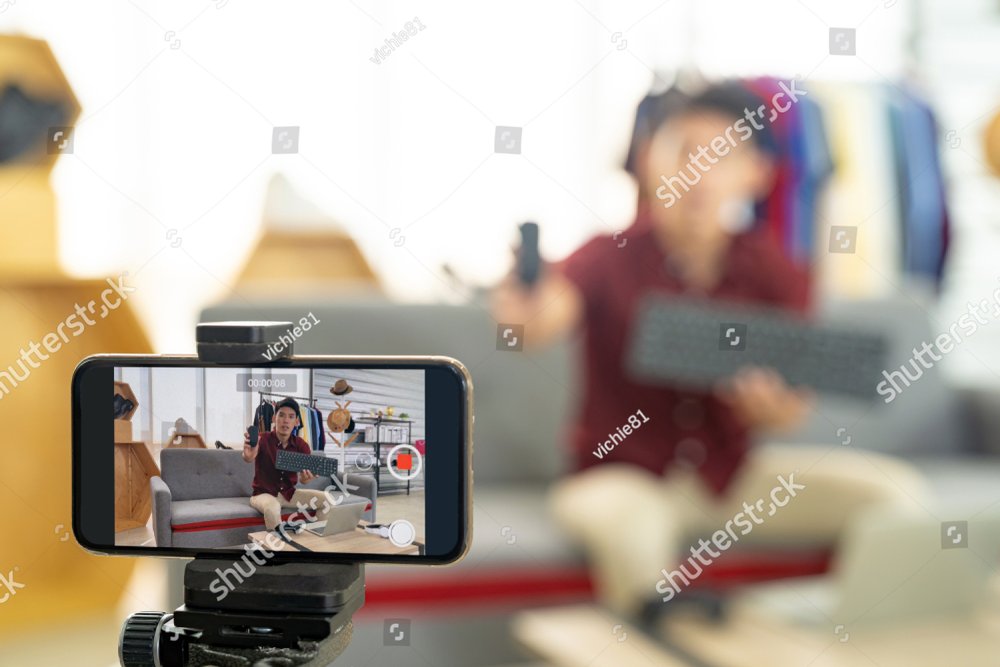 Young asian male online merchant blogger using smart mobile phone to recording live vlog video for review IT product goods. Online influcencer on social media concept. Focus on mobile phone