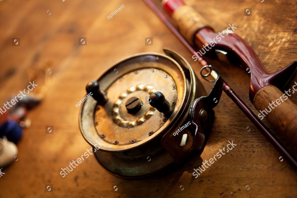 Vintage fishing reel, and rod on old wooden surface. Warm lighting. Sports  & Recreation Stock Photos