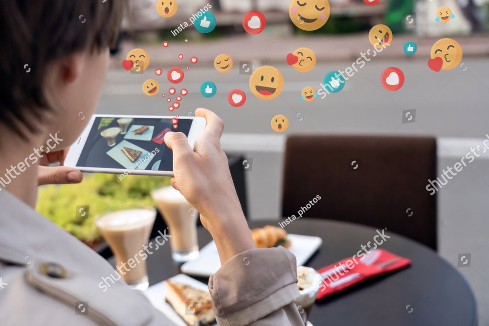 Influyente blogger mujer sostiene teléfono toma foto móvil de comida en un sitio de café en la mesa. Las jóvenes blogueras disparan a las redes sociales en instagram post en un smartphone tienen muchos me gusta el emoji frente a la vista de los hombros cerrados.