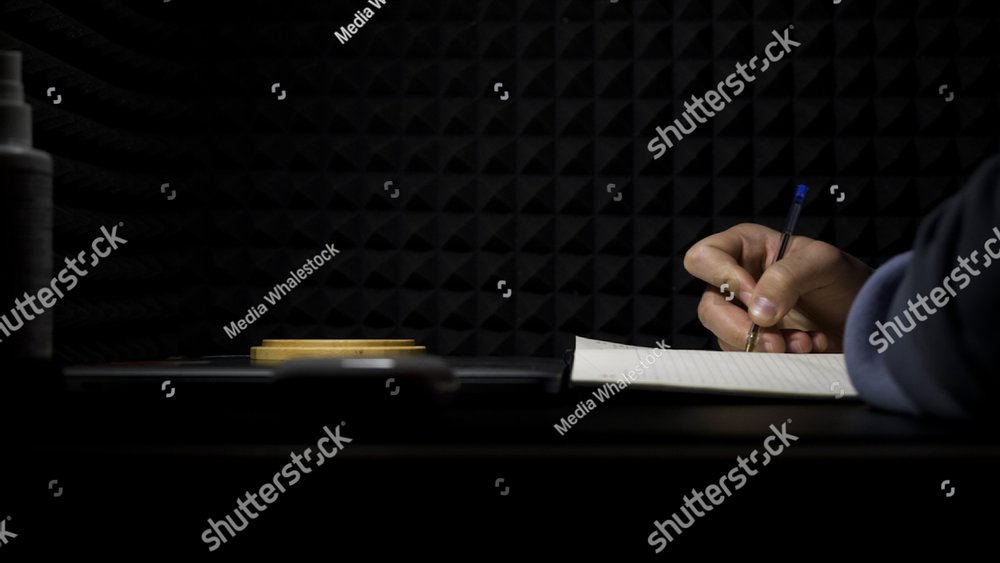 Concept of songwriting, side view of a man writing lyrics in a professional music studio. HDR. Process of creating a song by the author, musician writing text on a sheet of paper.
