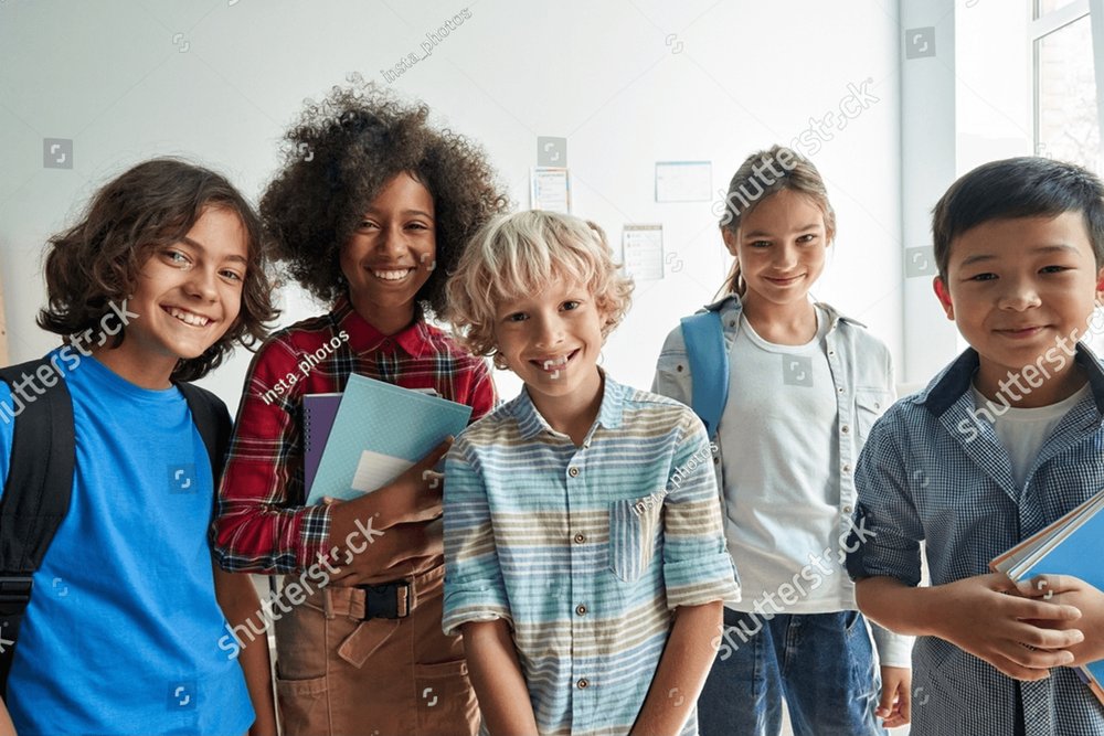 Feliz grupo diverso de estudiantes de primaria, niños, grupo, mirando una cámara de pie en el aula. Sonrientes multiétnicos geniales niños y niñas amigos posando juntos para un retrato grupal.