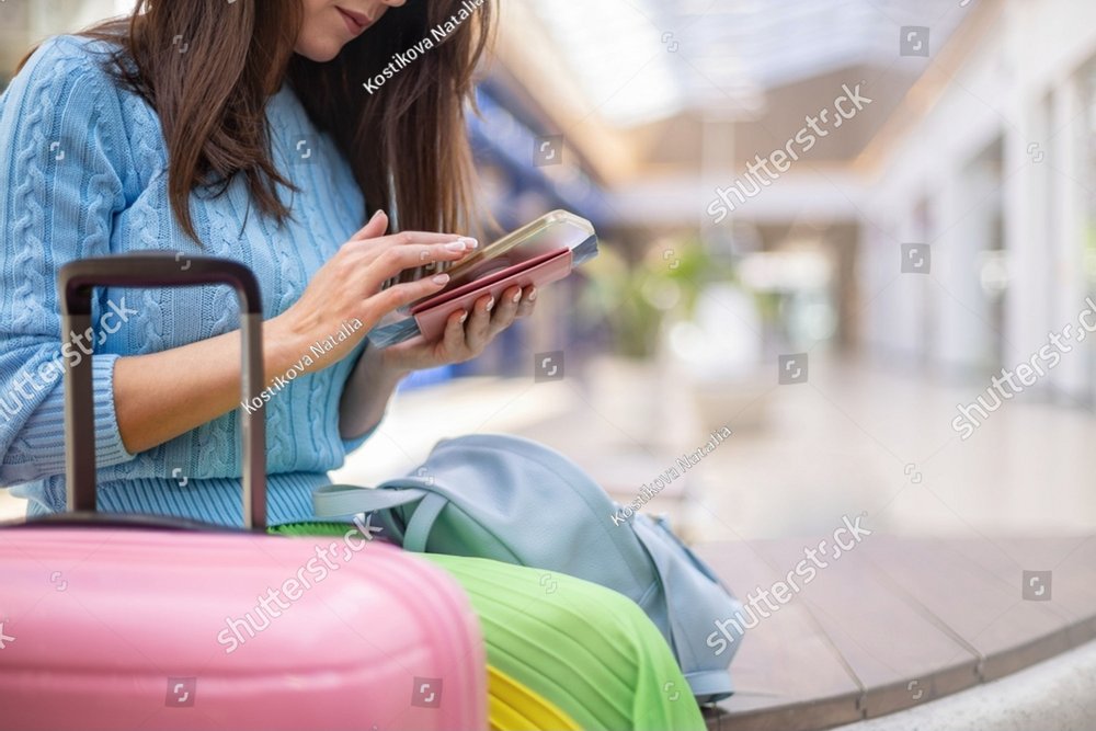 Focused elegant woman chatting surfing internet with coffee paper cup at lounge duty free area. Stylish female typing message use smartphone waiting departure at international airport terminal