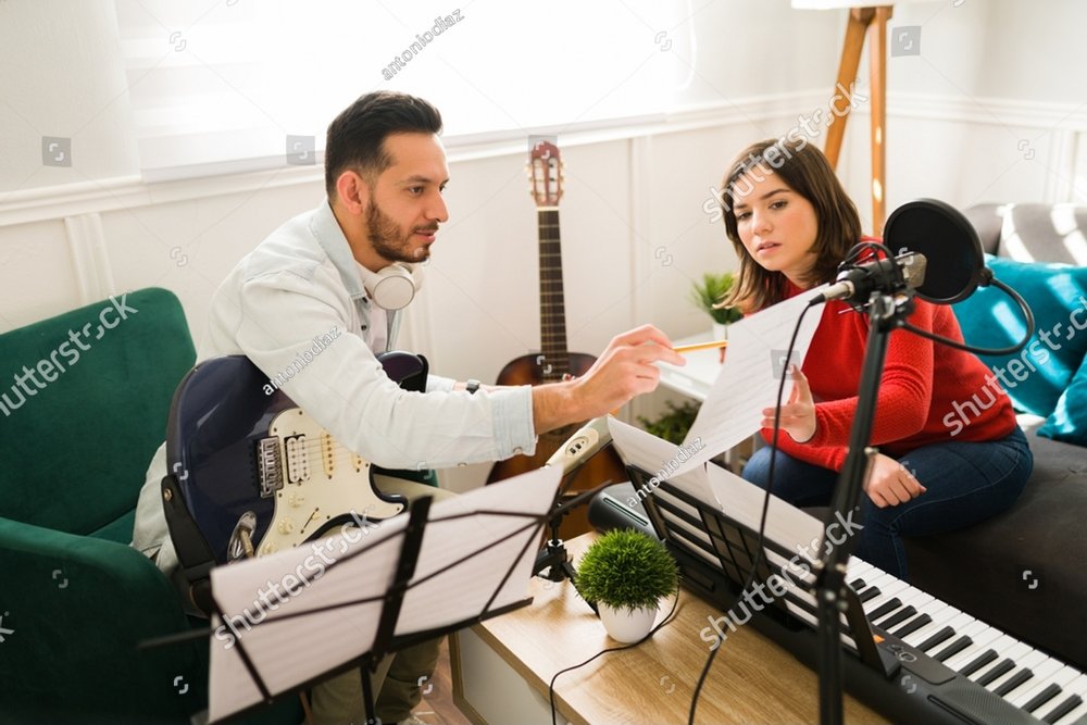 Writing the lyrics of a song. Attractive woman and man composing a new song on a music sheet while playing instruments