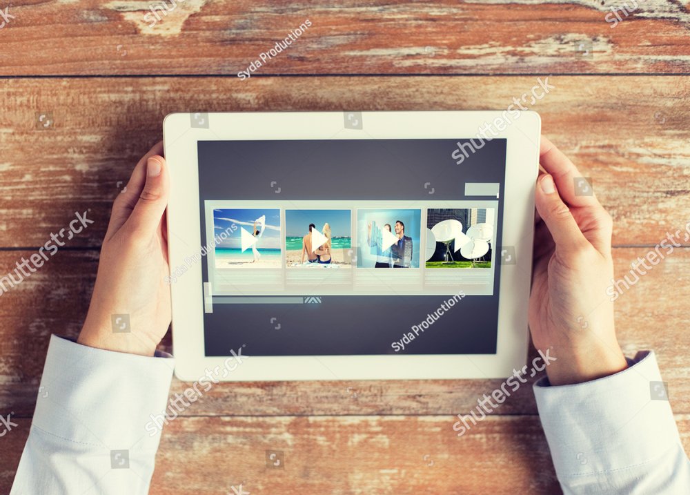 people, multimedia and technology concept - close up of hands with video gallery slideshow on tablet pc at table