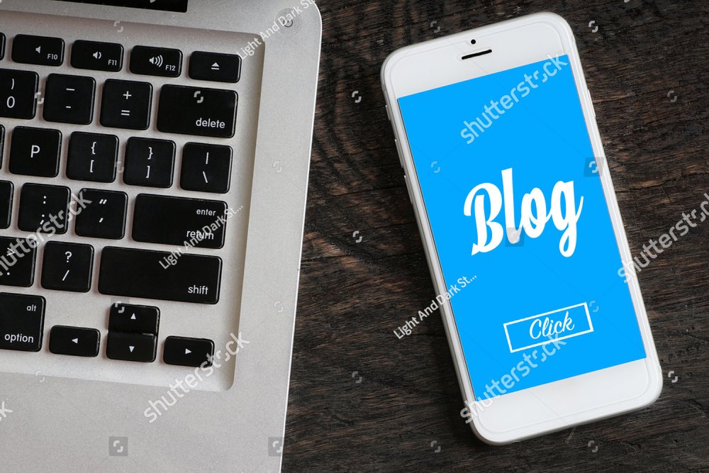 "Blog" words on smartphone with a laptop near it - website, multimedia and business concept