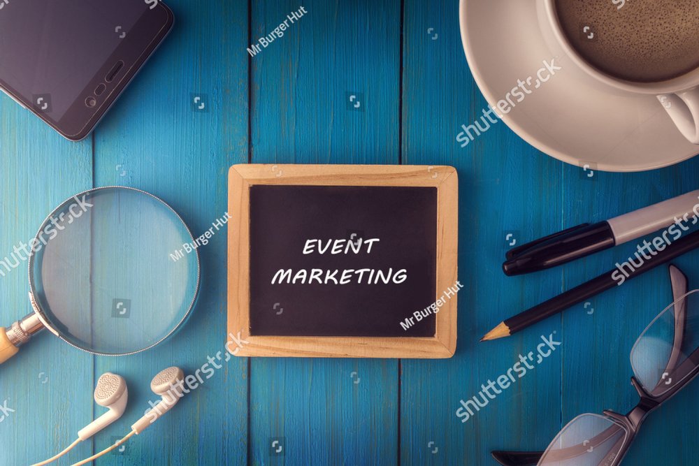 Top view of EVENT MARKETING written on the chalkboard,business concept.chalkboard,smart phone,cup,magnifier glass,glasses pen on wooden desk.