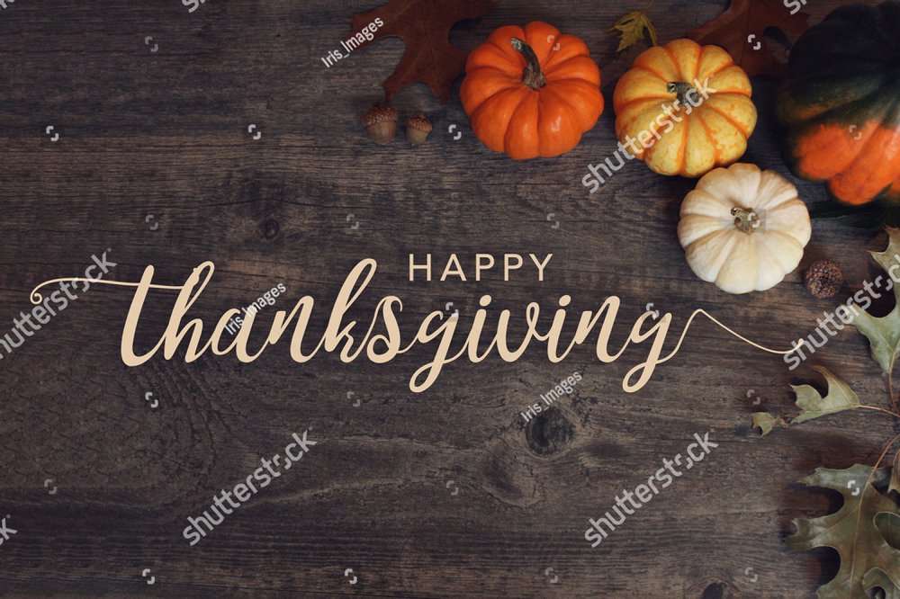 Happy Thanksgiving text with pumpkins and leaves over dark wood background