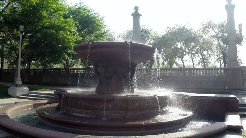 Backlit view of a water fountain in Grant Part in Chicago, Illinois, USA.  The camera then pans slowly to reveal the downtown skyline along Michigan Avenue.