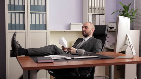 Businessman sitting in office with feet up on desk - Stock Photo