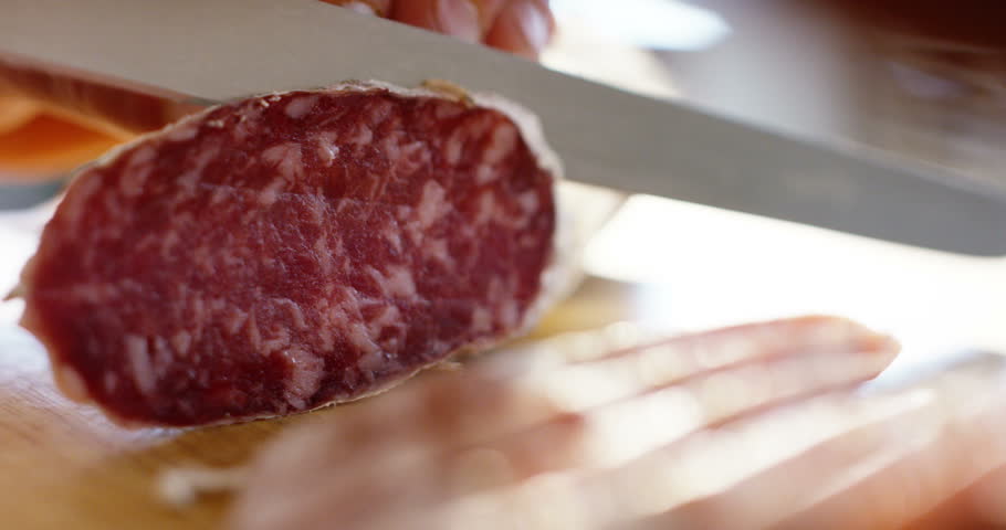 Super slow motion macro of a middle aged chef cutting salami with a knife on a wood board (close up) | Shutterstock HD Video #10013615