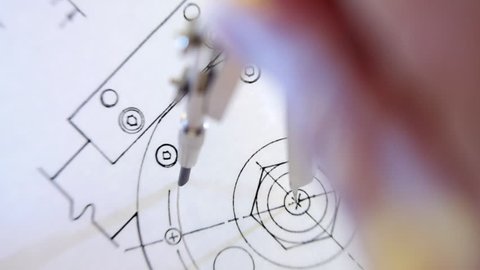 Compasses draws circle on the drawing. The camera is rotating. Closeup. Shallow depth of field