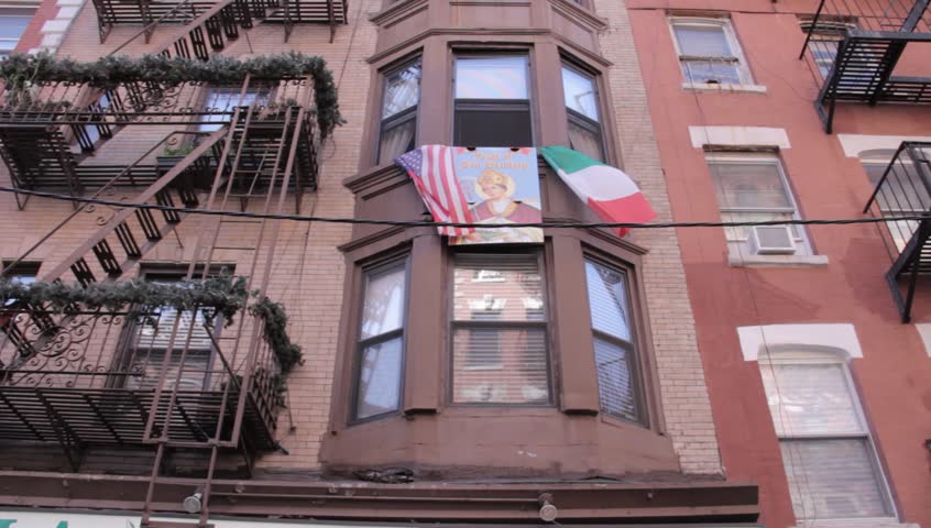 A daytime low angle shot of buildings and flags in Little Italy New York
