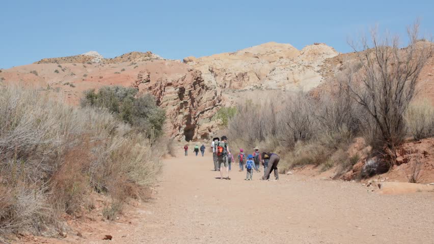 A family hiking through a desert wash near Goblin Valley State Park at Little Wild Horse slot canyon in Utah