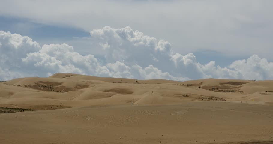 4k great white puffy cloud mass rolling over desert sand dunes.  gh2_08628_4k