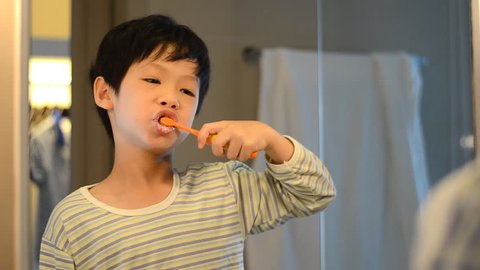 Little Asian boy brushing his teeth in bathroom