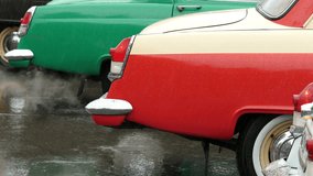 Old cars with colorful retro design in the rain. Only bumpers are visible. 4K UHD video.