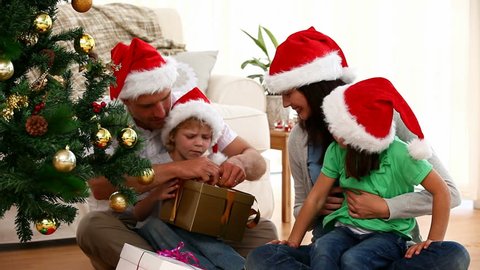 Cute family opening Christmas present sitting on the floor in the living-room Stock Video