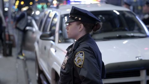NEW YORK - APRIL 26, 2015: attractive female police officer in uniform at night in slow motion, Times Square, NY. The NYPD enforces the law in the 5 boroughs of NYC, USA.