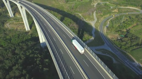 AERIAL: Container truck driving along the empty freeway