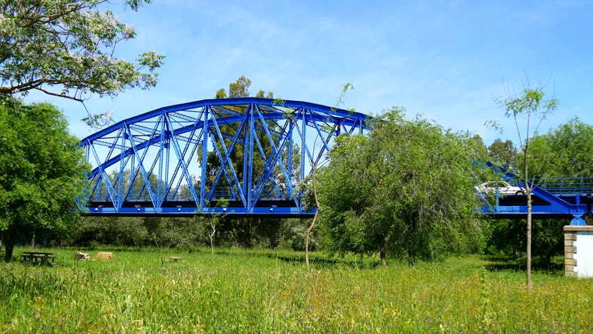 Blue iron bridge over river and meadow (4K)
