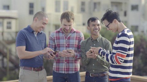 Group Of Happy Gay Friends Check Their Smart Phones And Share Photos With Each Other At A Rooftop Party In San Francisco (4K)