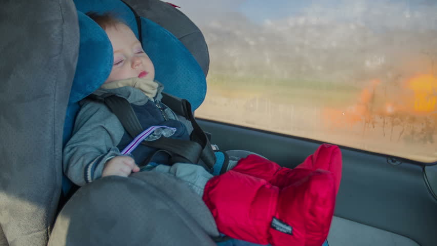 Cute boy slipping in a car chair. While driving on a high way the cut baby boy is slipping inn the chair on a sunny winter day footage in slow motion. Royalty-Free Stock Footage #10051325