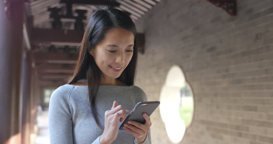 Woman using cellphone over chinese garden