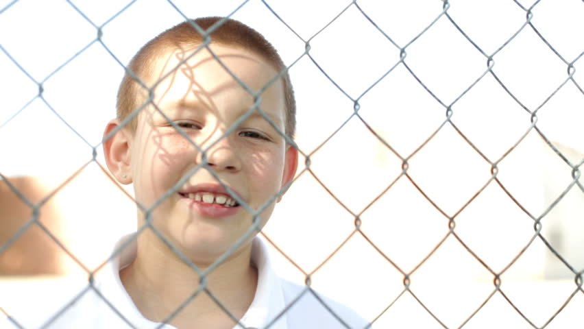 Happy boy laughing behind fence