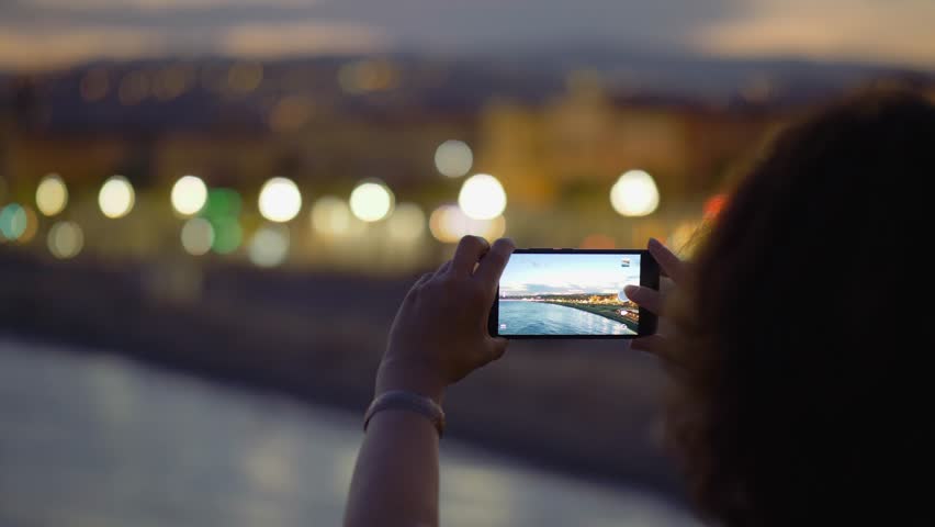 A woman is taking pictures of the embankment on her mobile phone. 4K, UHD