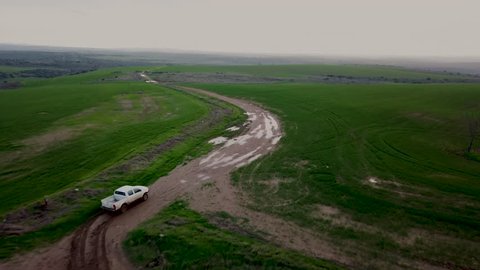 Aerial view of a pick-up truck driving thrugh a muddy field in winter