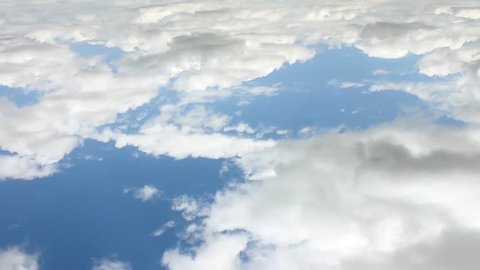 Airplane window view time lapse white rolling intensive clouds with very clean blue sunny lightness sky, relaxing colors, building, formating big angry mass active motion in horizon.