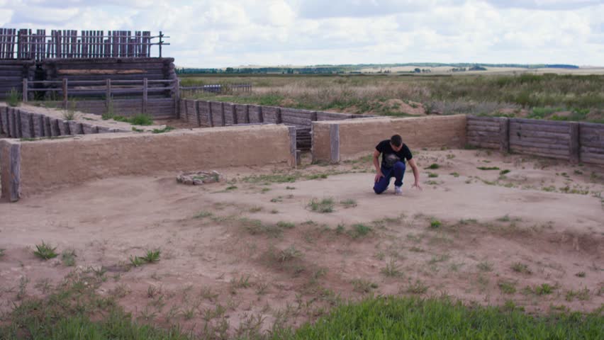 Man kneels on the ground and hand touches the ground - concept of native place. Man touching the ground in village - concept of memories about the place. Desperate man kneeling at dry cracked land