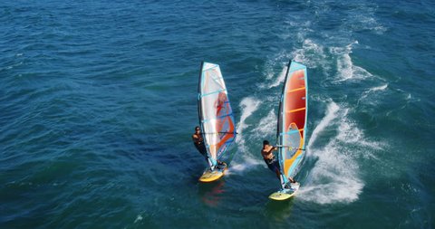 Cinematic aerial view of windsurfers sailing across the ocean