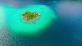 Green islands in mountain lake Eibsee beneath Zugspitze peak. Drone flight over a Germany's most beautiful glacier lake with clear emerald green water in Bavaria Alps. Germany, Central Europe. 