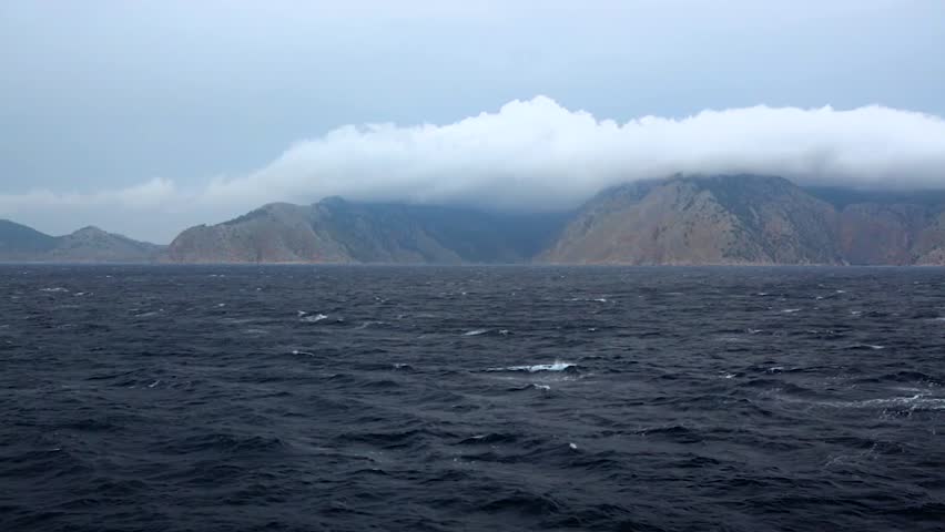 View of a hilly island in the Mediterranean Sea. Low clouds. Overcast. Greece
