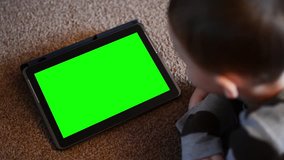 child (young boy) looks on tablet - green screen