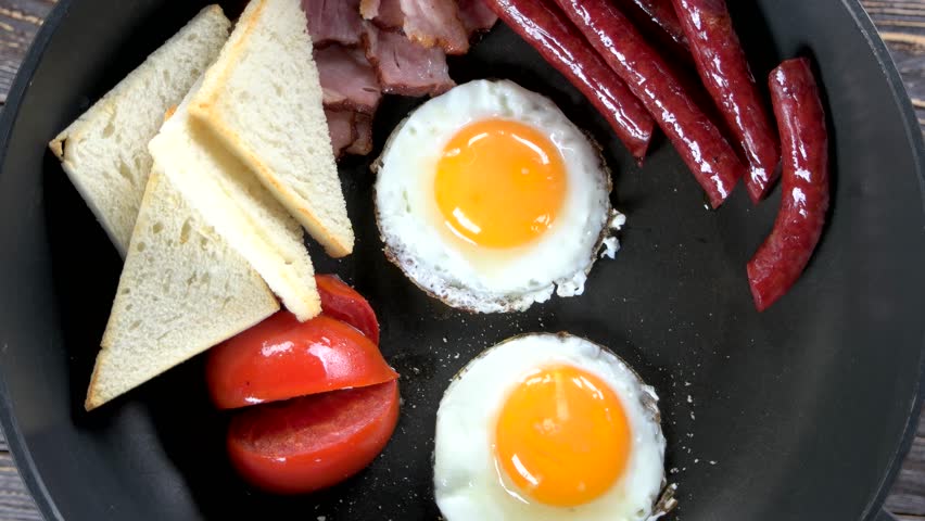 Fried eggs, sausages and tomato. Traditional English breakfast. | Shutterstock HD Video #1006566295