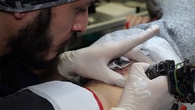 Professional tattoo artist makes a tattoo on a young girl's body. Tattoo artist make tattoo at the studio, close up