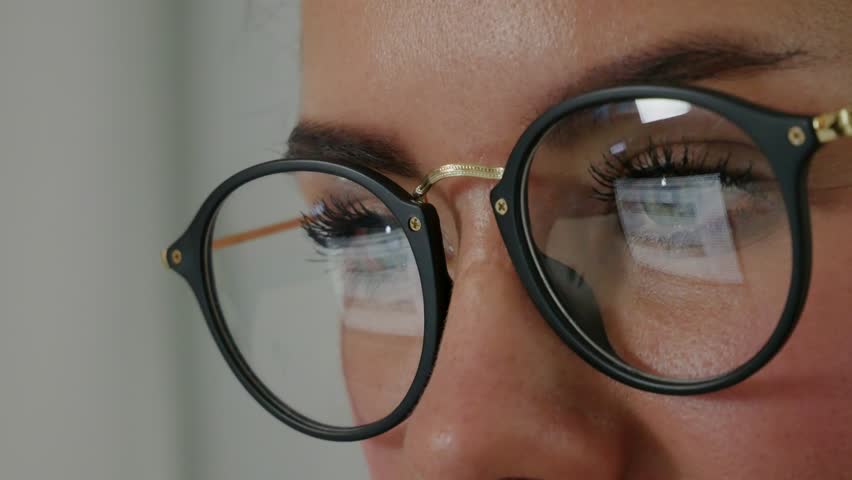 Reflection at the glasses of young woman: looking a site (side view) Beautiful girl works on internet close up Royalty-Free Stock Footage #1006570744