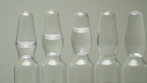 Ampoules with a clear solution for injection stand in a row. panning close-up