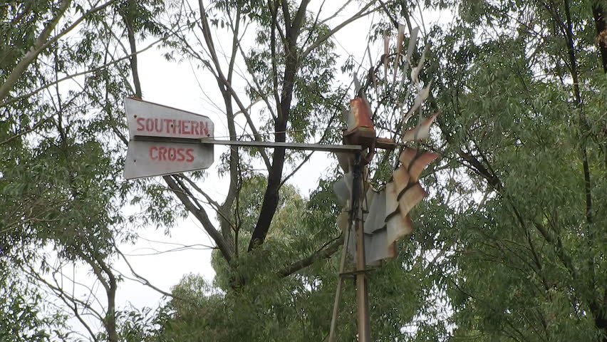A medium shot of trees and a windmill with a sign.